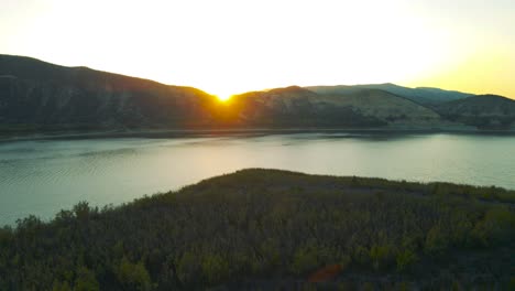 Aerial-view-of-the-sun-setting-behind-mountains-at-vail-lake