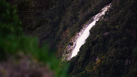 Powerful-water-stream-falling-down-rocky-slope-in-New-Zealand,-static-view