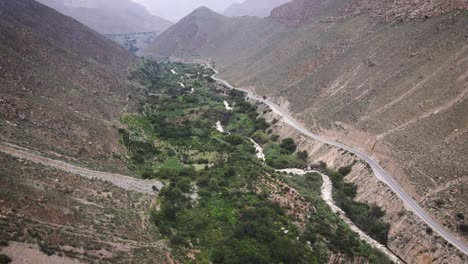 Descending-drone-shot-of-a-green-valley-and-a-river-next-to-a-highway-in-the-mountains-of-Peru