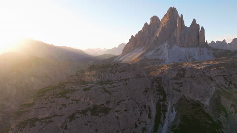 Glowing-sunlit-Tre-Cime-mountains-aerial-view-flying-across-radiant-South-Tyrol-extreme-mountaineering-landscape