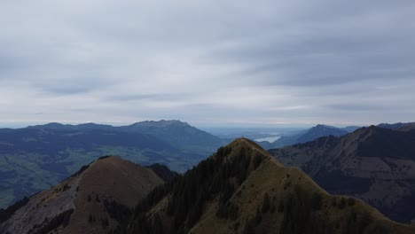 Man-standing-at-the-edge-of-a-mountain-peak-in-Switzerland