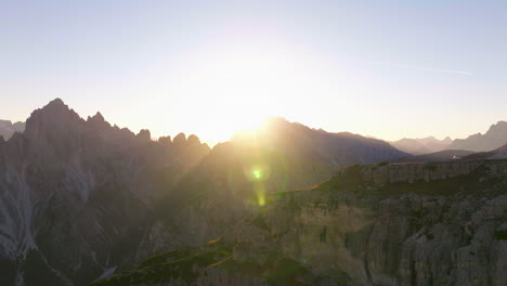 Tre-Cime-sunrise-mountain-peaks-aerial-view-flying-across-extreme-rocky-South-Tyrol-valley-terrain