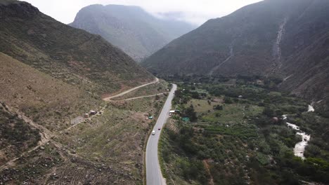 Drone-shot-of-a-car-in-a-road-in-between-mountains-in-the-highlands-of-Peru