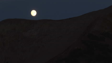 Una-Luna-Llena-Desaparece-Lentamente-Detrás-De-Una-Línea-De-Cresta-En-Las-Montañas-Rocosas-De-Colorado-En-Medio-De-La-Noche