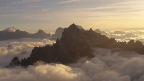 Golden-Sunrise-Silueteado-Tirol-Del-Sur-Tre-Cime-Montañas-Rodeadas-De-Nubes-Celestiales-Vista-De-órbita-Aérea