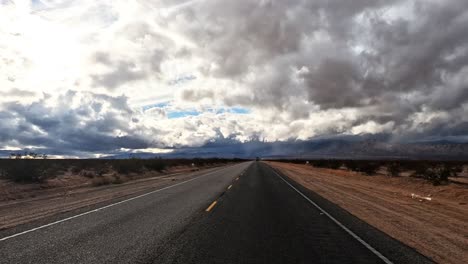 Nubes-Ominosas-Oscuras-Sobre-Una-Carretera-Solitaria-A-Través-Del-Desierto-De-Mojave---Hiperlapso-Del-Punto-De-Vista-Del-Conductor