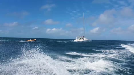 SAILBOAT-SAILING-ON-CARIBBEAN-SEA-with-dinghy-tied-to-behind,-WAVES-AND-SPLASH-WATER
