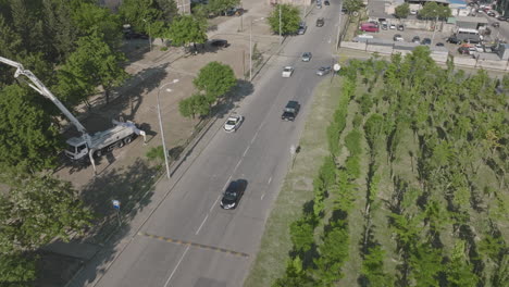 Aerial-tracking-shot-of-a-black-car-merging-with-traffic-on-a-busy-street