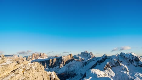 Blue-sky-and-flying-clouds-over-snowy-and-frozen-peak-of-mountains-during-golden-hour---Time-lapse-footage
