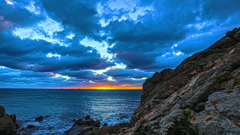 Sunset-on-the-horizon-of-across-the-fjord-as-seen-from-the-rocky-shoreline---dynamic-sliding-motion-time-lapse-and-cloudscape