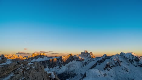 Time-lapse-shot-of-Beautiful-sunset-at-horizon-and-rising-full-moon-at-sky-over-snowy-mountain-summits