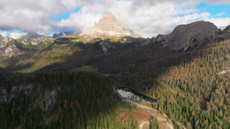 Stunning-lush-dense-Tre-Cime-woodland-forest-aerial-view-and-majestic-Dolomite's-in-distance