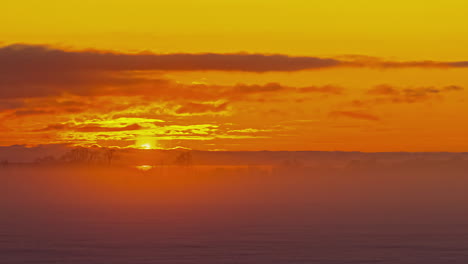 Epischer-Goldener-Sonnenaufgang-Mit-Fliegenden-Wolkenlinseneffekt-Und-Nebel-Auf-Schneebedecktem-Winterfeld---Zeitraffer