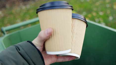 Woman's-hand-throwing-away-empty-paper-coffee-cup-in-recycling-bin