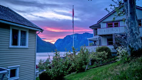 Time-lapse-shot-of-waving-Norwegian-flag-in-front-of-fjord-and-mountains-at-sunset