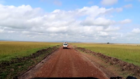 Vehicles-go-on-a-dirt-road-on-a-safari-looking-for-animals-in-Kenya,-Africa