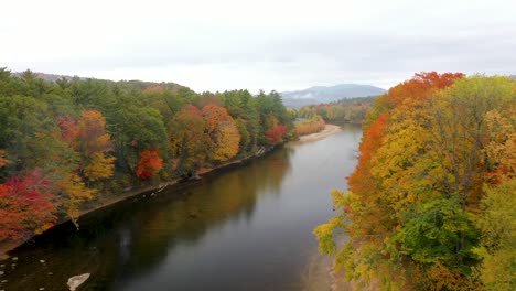 Flyover-aerial-shot-over-river-in-New-England-during-peak-foliage-season