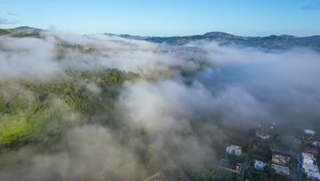 Stunning-magic-aerial-view-of-the-mountains-with-dense-fog-and-a-river,-winter-weather-in-the-caribbean-in-the-morning