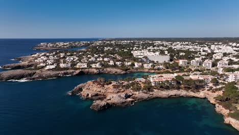 Aerial-view-with-drone-viewing-the-town-of-Cala-d'Or-with-white-houses,-cliffs-and-the-mediterranean-sea