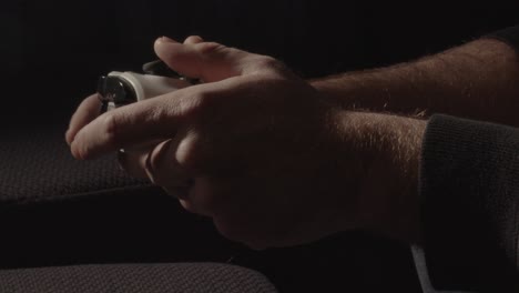 Close-up-of-male-hands-playing-with-videogame-controller-while-light-emitted-by-television-is-flashing