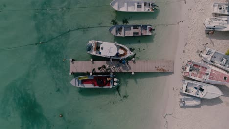 Top-view-people-stand-on-wooden-dock-get-on-motorboat,-los-roques-venezuela