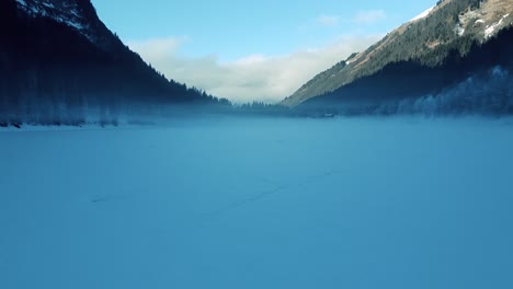 Zugefrorener-See-Mit-Berglandschaft,-Kamera-Bewegt-Sich-über-Eisoberfläche-Und-Bewegt-Dann-Den-Fokus-Auf-Hügel
