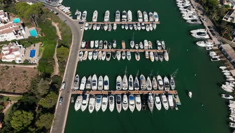 Aerial-view-of-drone-flying-over-cala-d'Or-harbor-and-beach-of-Mallorca-filled-with-boats-and-yachts