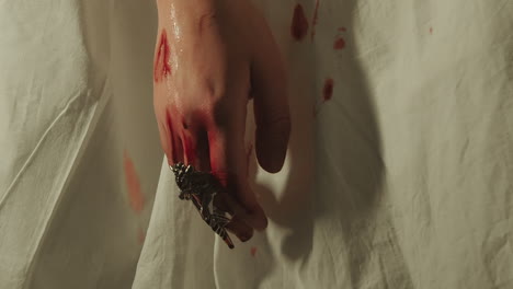 Blutige-Hand-Mit-Einem-Großen-Dekorativen-Ring-Und-Blut,-Das-Auf-Ein-Weißes-Blatt-Tropft