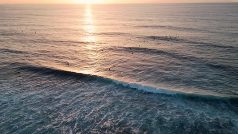 Luftaufnahme-Einiger-Surfer,-Die-Bei-Sonnenuntergang-Auf-Die-Wellen-Warten