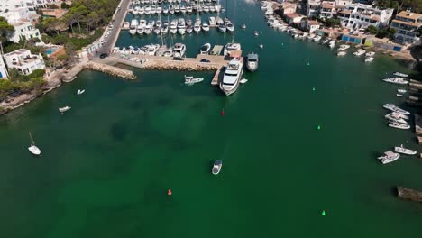 Aerial-view-of-drone-flying-to-cala-d'Or-harbor-of-Mallorca-filled-with-boats-and-yachts-during-summer