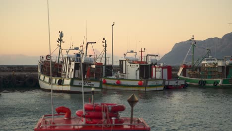 Fisher-boats-are-swinging-on-light-sea-waves-while-being-docked-at-the-port-in-Cape-town,-South-Africa