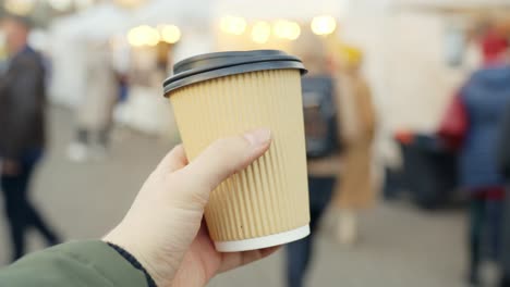 Girl-holds-plastic-coffee-cup-on-a-busy-street,-commercial-background