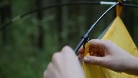 Close-up-shot-of-man-setting-up-a-tent-while-camping-in-the-woods