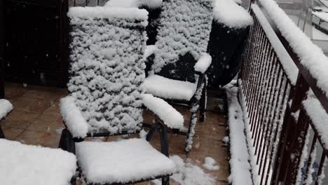 Winter-on-the-balcony,-metal-chairs-covered-in-snow