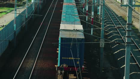 Ein-Langsamer-Güterzug,-Der-Mit-Strom-Betrieben-Wird,-Fährt-Durch-Eine-Ländliche-Gegend-In-Österreich,-Während-Er-Von-Einem-Schnellen-Personenzug-überholt-Wird