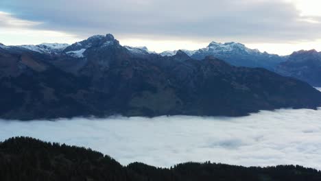 Descending-aerial-shot-of-a-fog-covered-valley-in-the-Swiss-alps-mountain-range