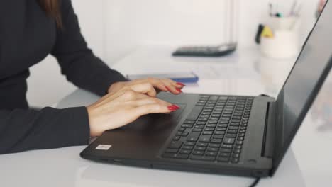 Close-up-of-female-hands-working-on-a-laptop-on-the-background-of-the-office