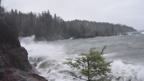 Rough-storm-waves-crashing-against-rock-cliffs-on-a-gloomy-day,-slow-motion