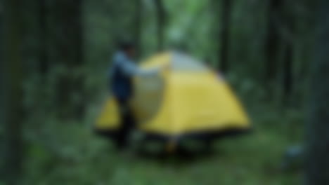 Blurred-shot-of-couple-setting-up-a-tent-while-camping-in-the-woods
