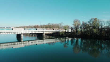Ein-Langer-Güterzug-Mit-Kartoffeln,-Der-über-Eine-Eisenbahnbrücke-über-Einen-Schönen-Fluss-In-Österreich-Fährt