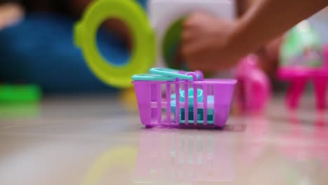 Adorable-little-child-playing-with-toy-washing-machine-and-clothes-indoors