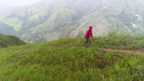 Mujer-Joven-Caminando-Sola-En-La-Montaña-Verde,-Usa-Chaqueta-Roja,-El-Jarillo-Venezuela