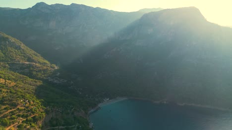drone-shoot-of-a-morning-view-of-a-beach-with-the-sun-shining-behind-the-mountain---Kabak,-Turkey