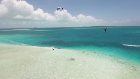 Two-men-kitesurf-jump-and-cross-Caribbean-sea,-drone-shot-Los-Roques-archipelago