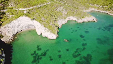 drone-flying-high-in-circulair-motion-with-the-camera-tilting-up-slowly-over-the-rugged-coastline-of-Gargano-national-park,-Italy-in-4k