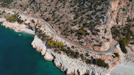 aerial-view-of-a-mountain-road-next-to-the-mediterranean-ocean-on-a-sunny-day-in-Fethiye---Turkey