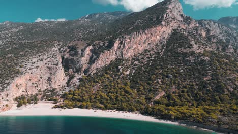 drone-shot-of-a-white-sand-beach-in-the-bottom-of-a-mountain-with-blue-water-sea---Fethiye---Turkey