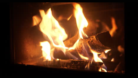 Close-up-shot-Wood-log-thrown-Into-home-fireplace,-glowing-flames
