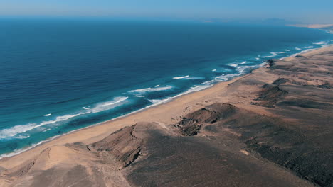 Aerial-shot-at-a-high-altitude-over-the-Cofete-natural-park-on-the-island-of-Fuerteventura-and-where-you-can-see-its-fantastic-beach-and-the-beautiful-mountains-in-the-area