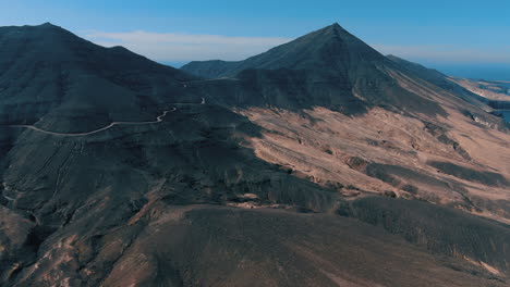 Fantastische-Luftaufnahme-über-Den-Naturpark-Cofete-Auf-Der-Insel-Fuerteventura-Und-Wo-Sie-Die-Straßen-Sehen-Können,-Die-Auf-Großen-Vulkanbergen-Gebaut-Wurden